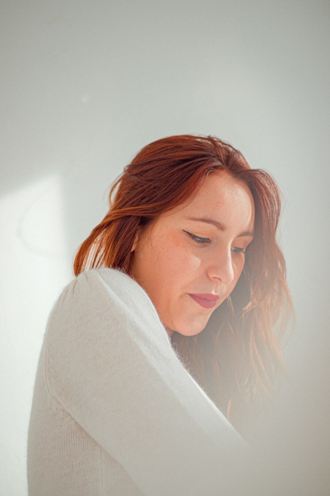 Portrait of a woman with auburn hair wearing a light jumper